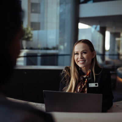 A receptionist smiles at a customer from behind the desk.