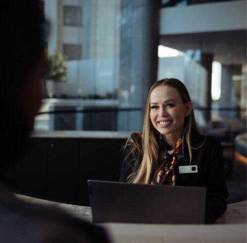 A receptionist smiles at a customer from behind the desk.