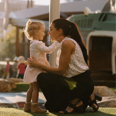 A mom picks up her daughter from daycare and give her a hug.
