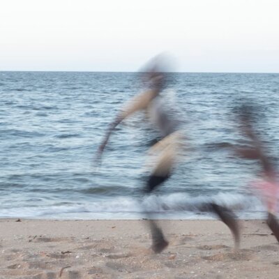 A photograph taken by Maria Fredericks capturing two people running along the shore of a beach.